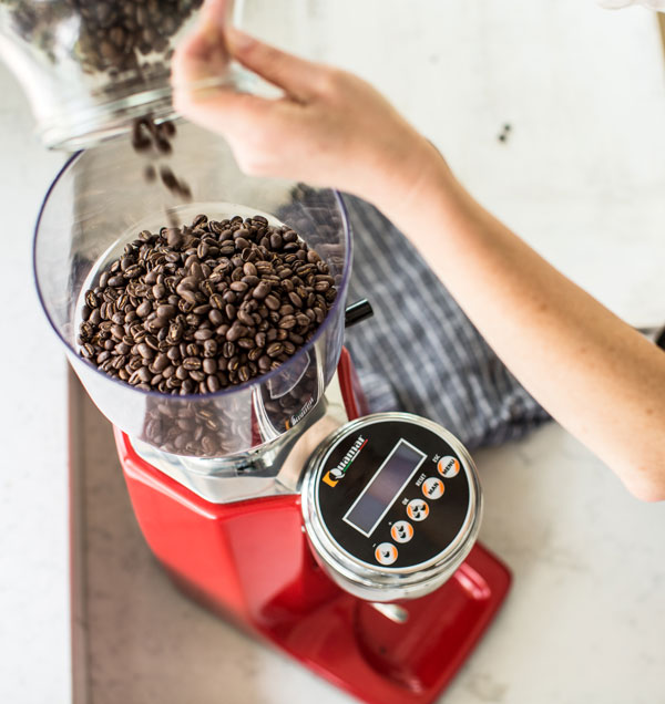 pouring coffee beans into grinder